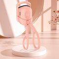 Portable electric heated eyelash curler in pink, compact design for long-lasting curls, USB-rechargeable, ergonomic handheld tool.